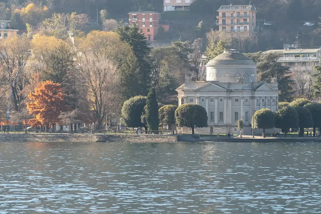 The Tempio Voltiano among autumn trees on the Como lakeshore seen from the water