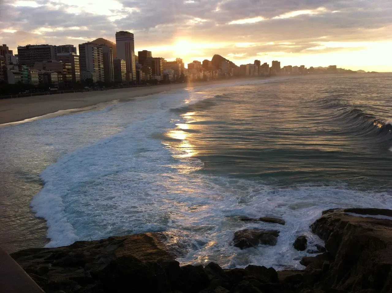 Waves breaking on Copacabana beach at sunset with the skyline behind