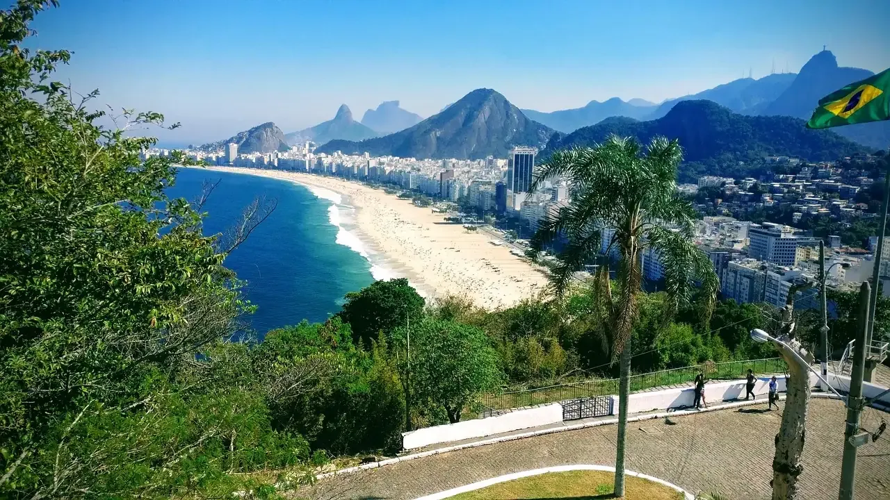 The curve of Copacabana beach seen through palm trees from Leme