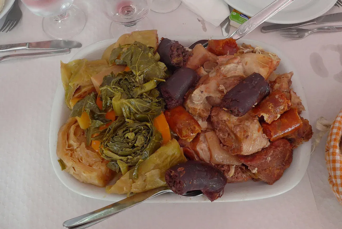 A plate of cozido a portuguesa with meats, sausage and vegetables