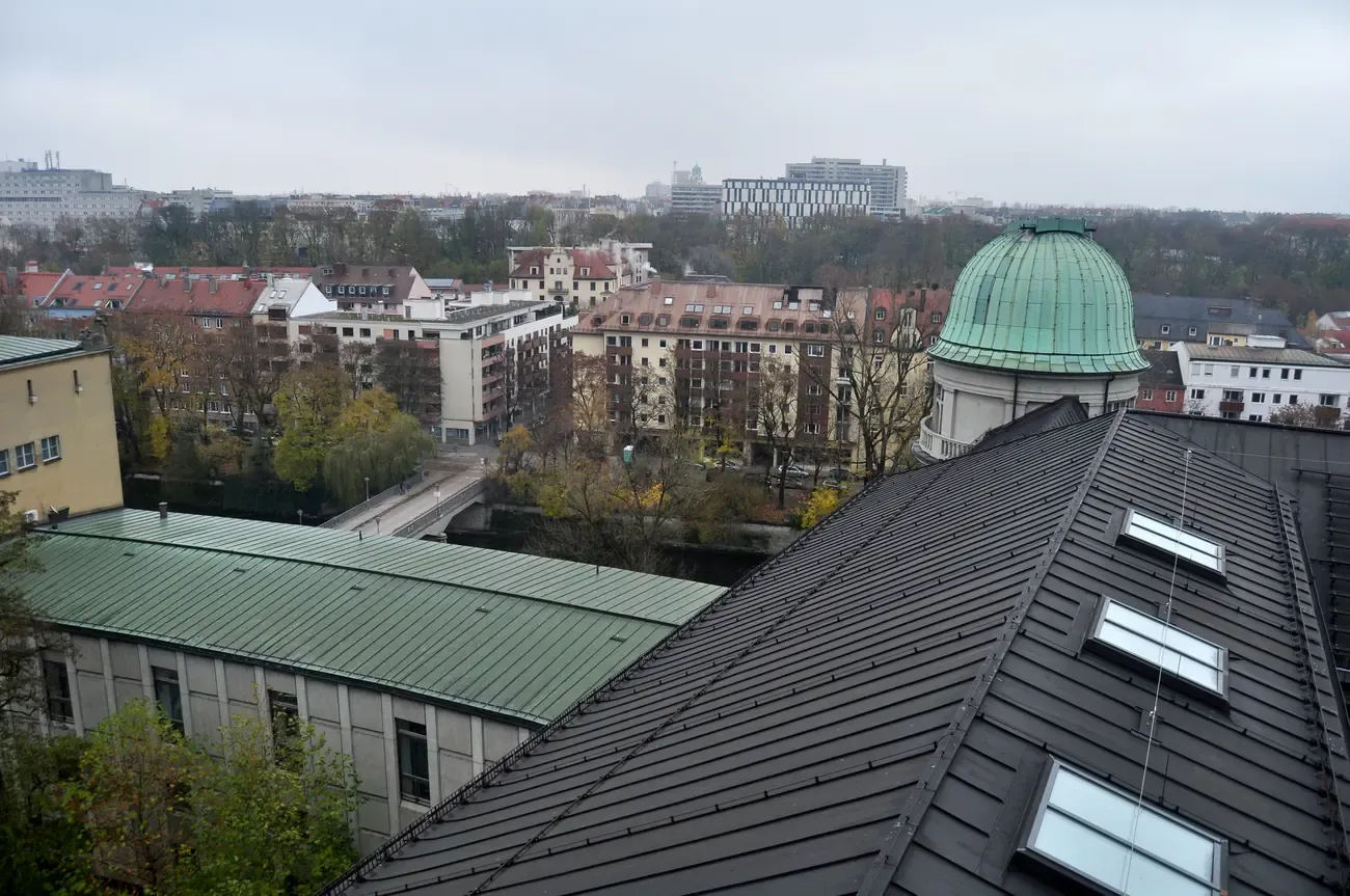 Copper observatory dome on the roof of the Deutsches Museum with the Isar and the rooftops of Munich behind it