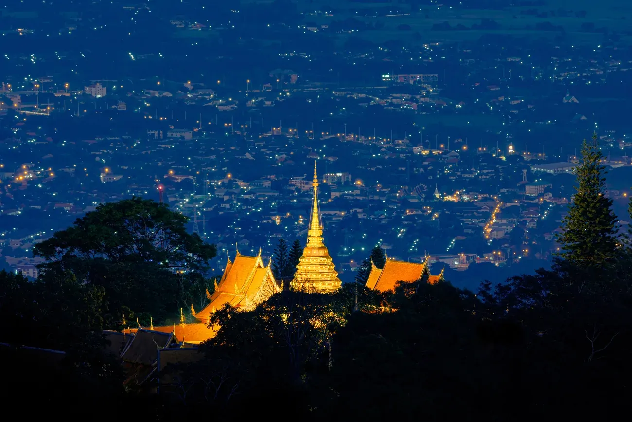 The golden chedi of Doi Suthep above the lights of Chiang Mai at night