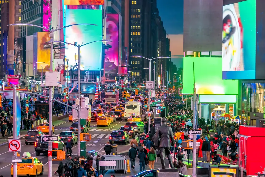 Duffy Square statue overlooking busy traffic and neon billboards in Times Square, New York City