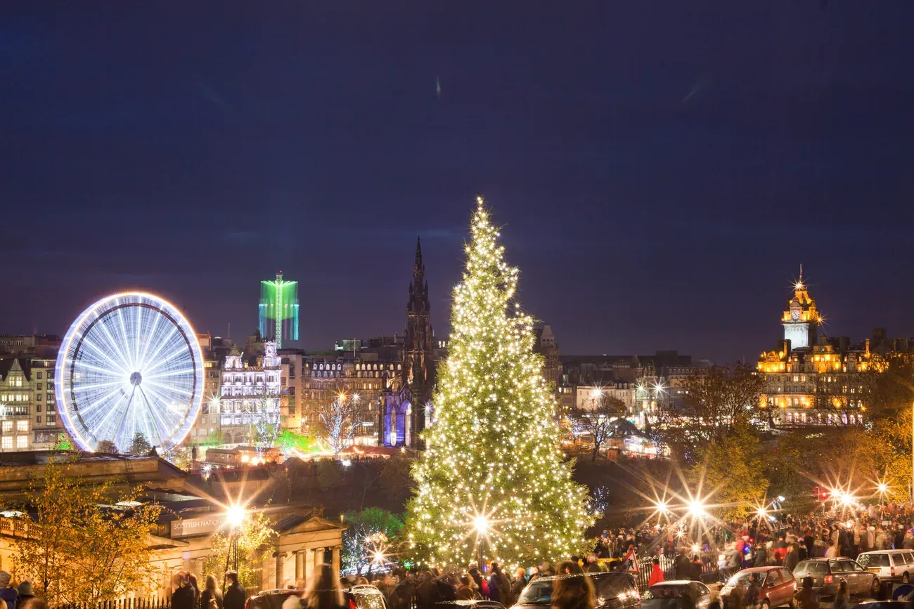 Edinburgh at Christmas at night, with the big wheel, the Scott Monument, a lit Christmas tree and the Balmoral clock tower