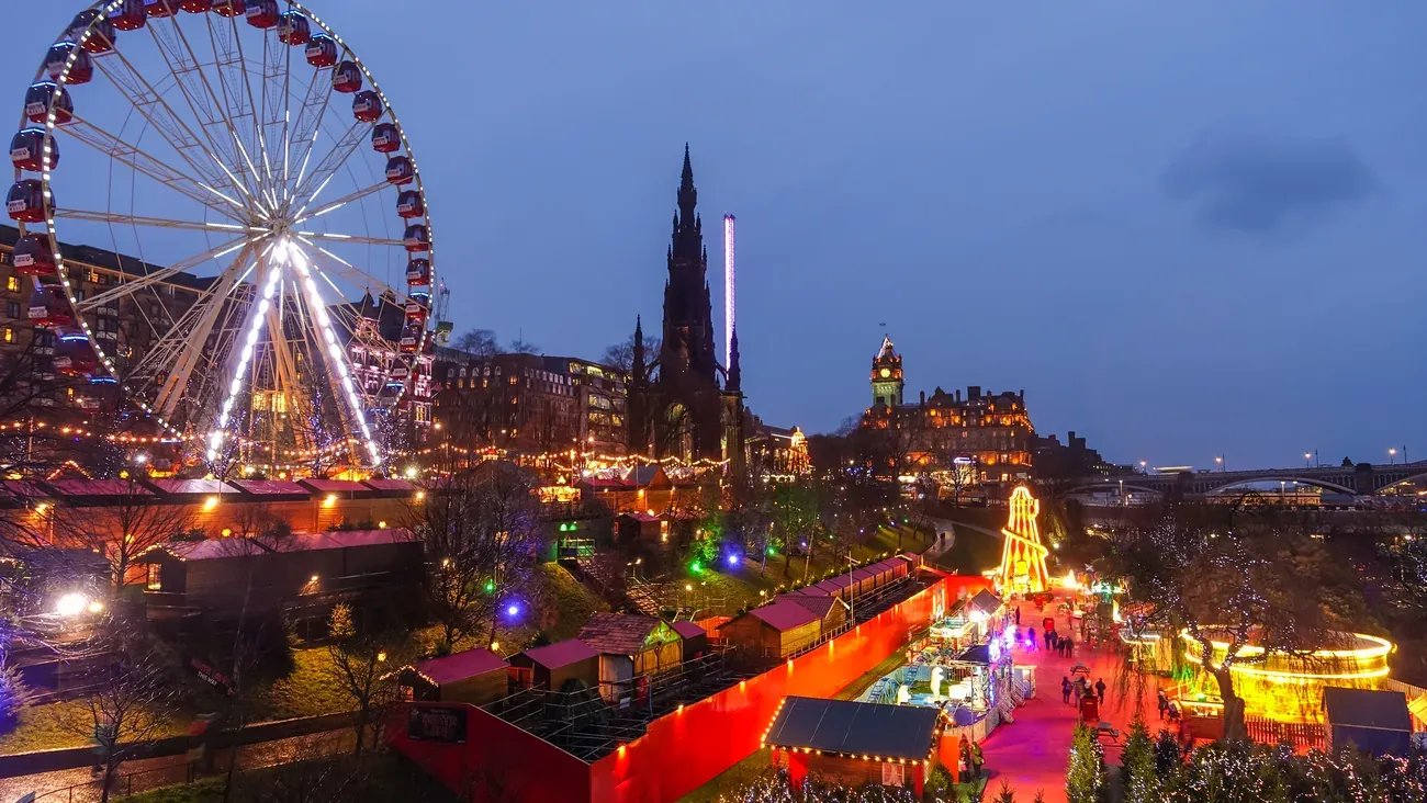 Edinburgh's Christmas market in East Princes Street Gardens at dusk, with the big wheel and the Scott Monument