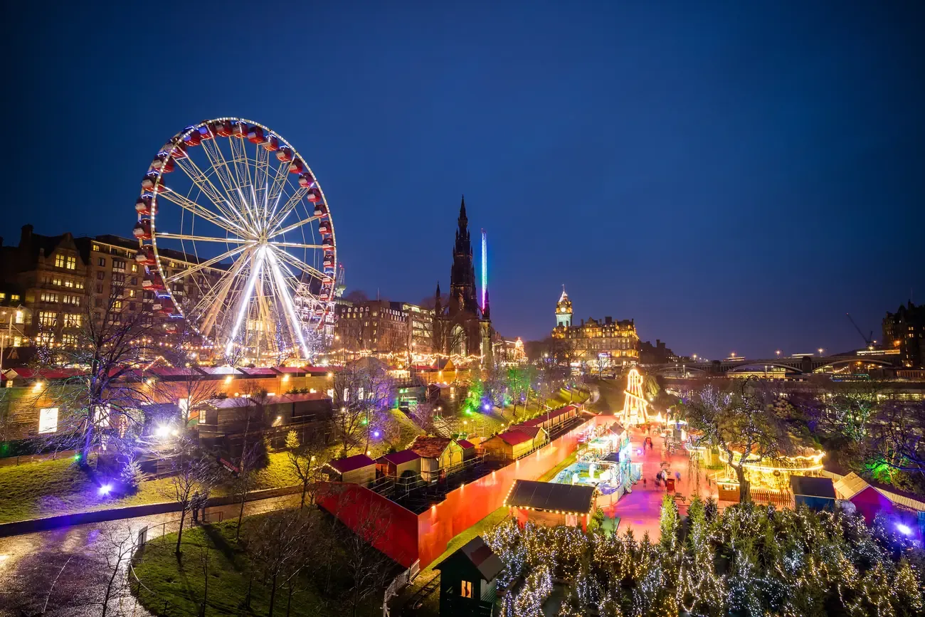 Christmas market stalls and the big wheel in East Princes Street Gardens, Edinburgh, at night