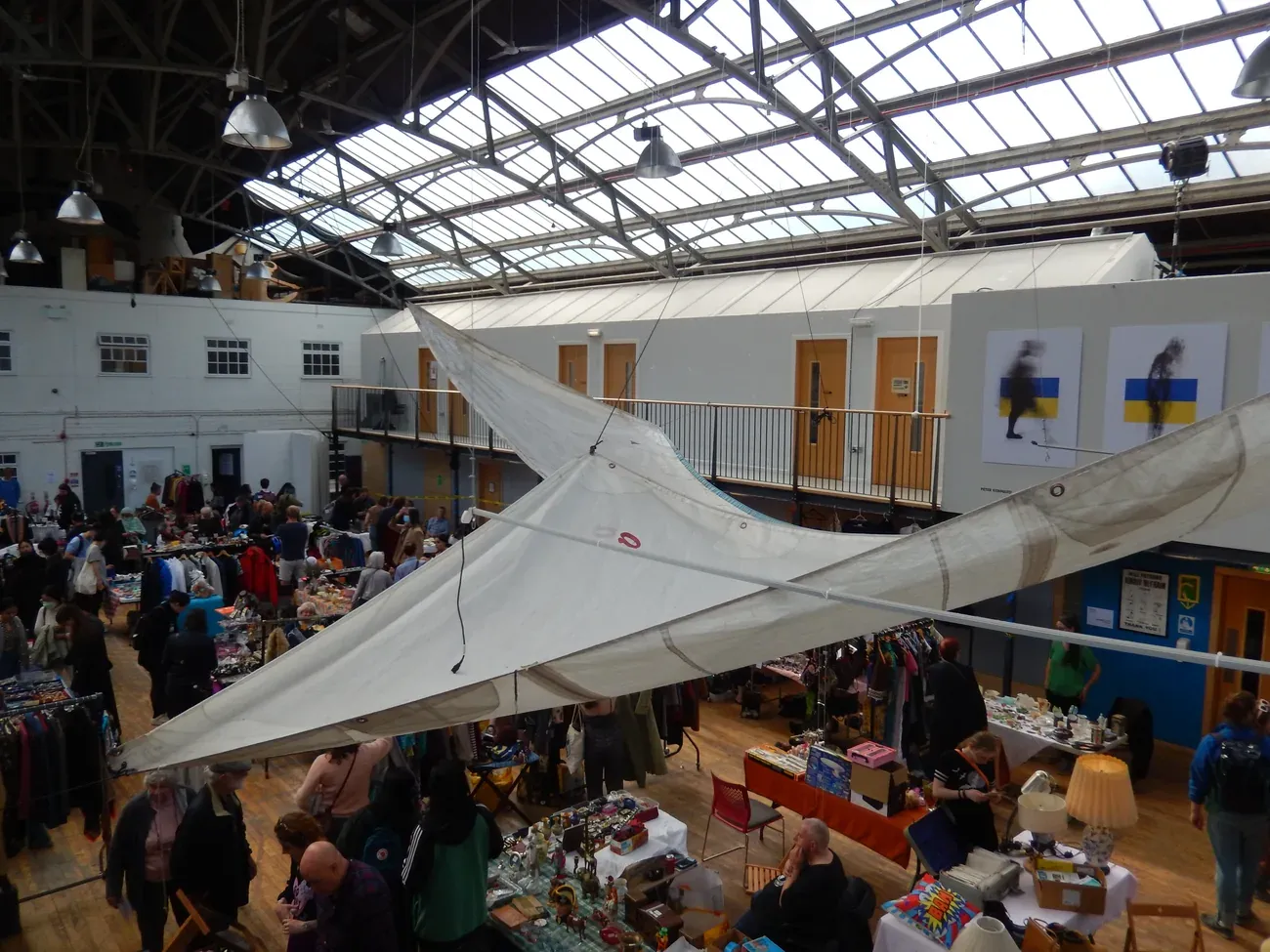 Market stalls and shoppers inside the glass-roofed Out of the Blue Drill Hall in Leith, Edinburgh