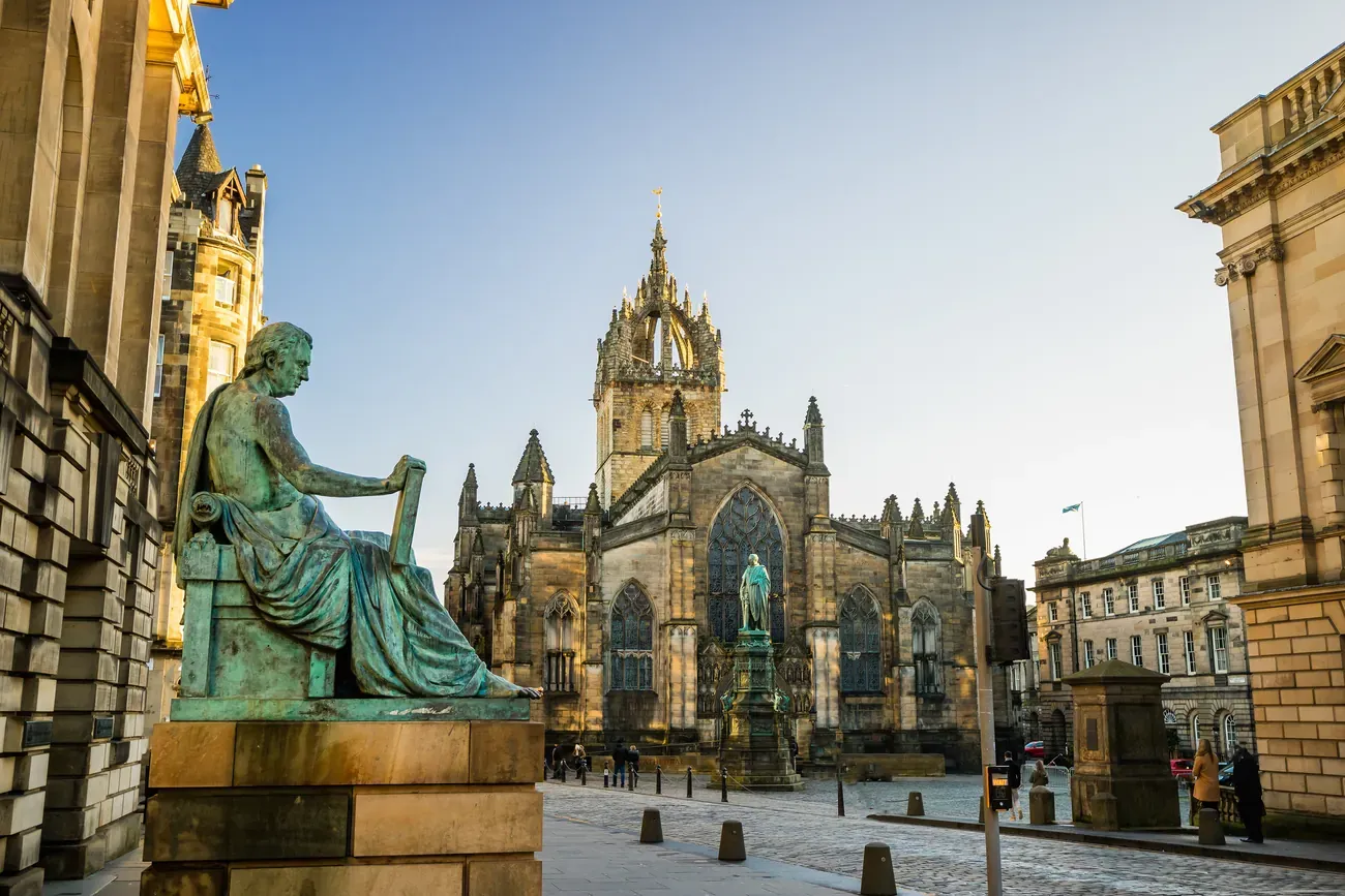 Crown spire of St Giles Cathedral on the Royal Mile in Edinburgh, with the seated bronze statue of David Hume in the foreground