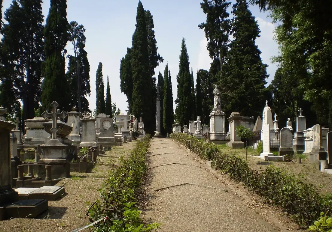 White marble tombs and cypress trees along a gravel path in the English Cemetery in Florence