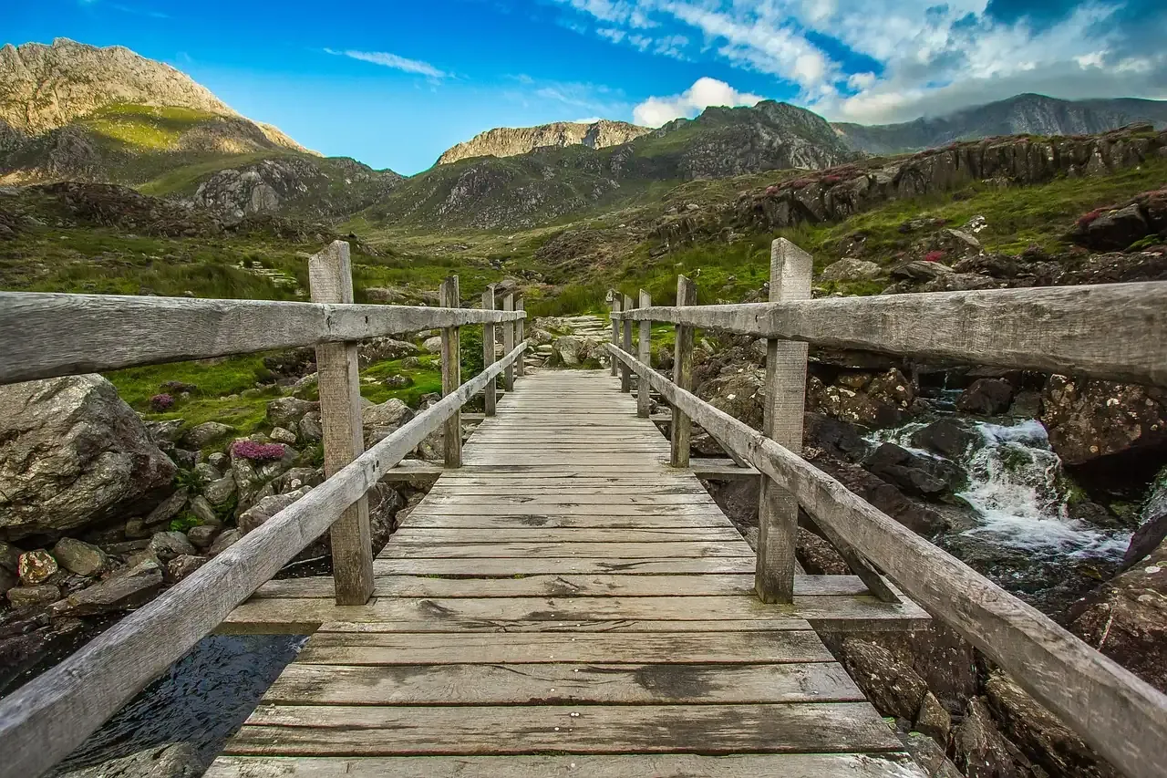 Wooden footbridge over a stream below the peaks of Eryri in north Wales
