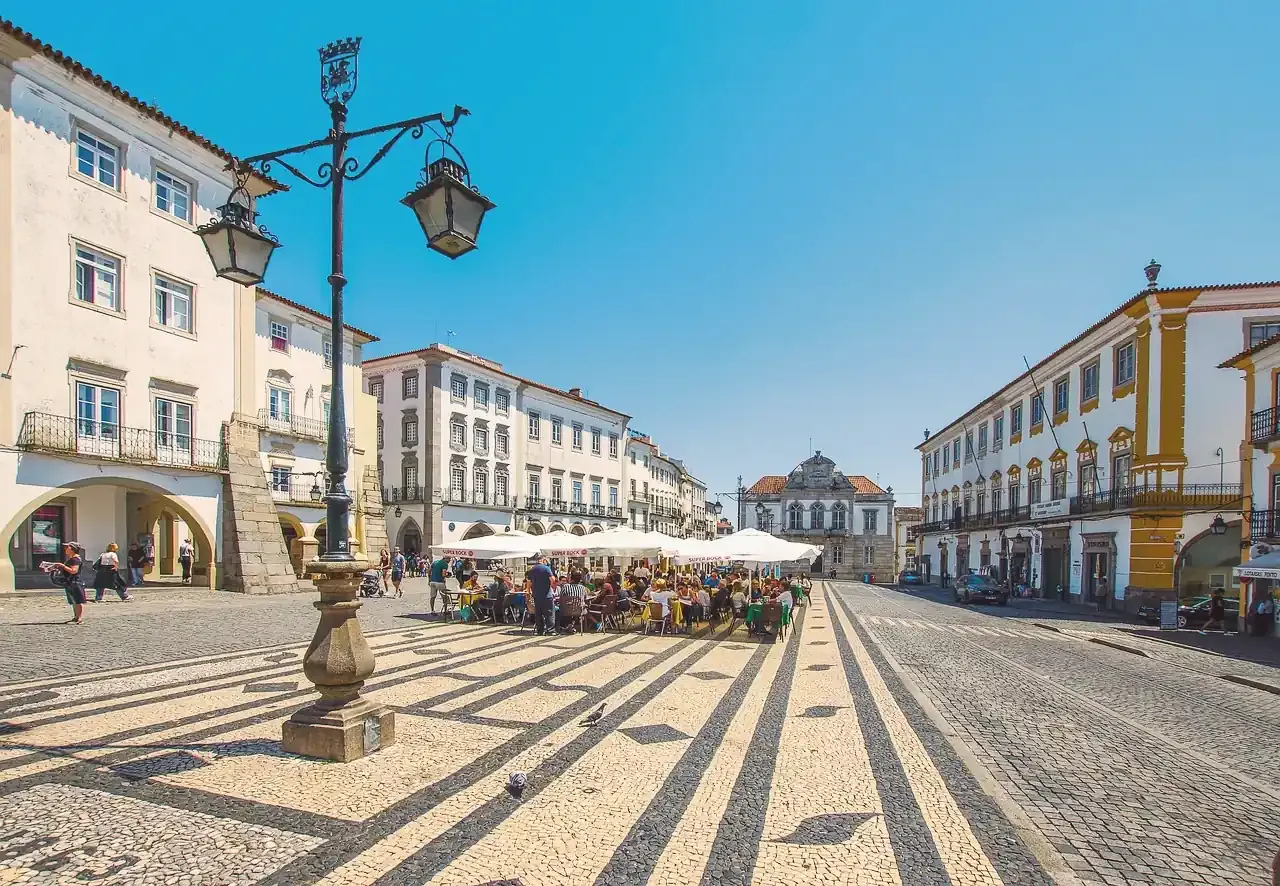 Arcaded whitewashed houses and patterned paving along Praca do Giraldo in Evora
