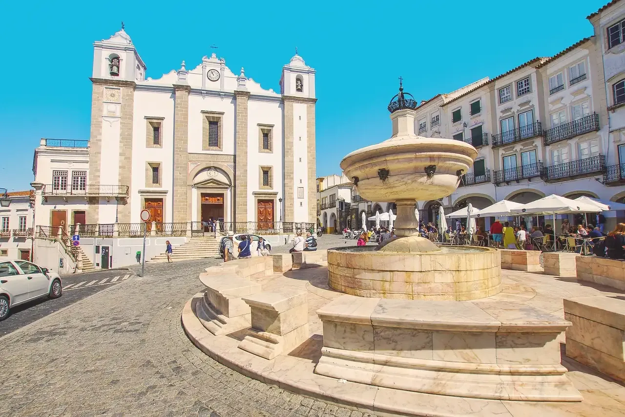 The marble fountain and the church of Santo Antao on Praca do Giraldo in Evora