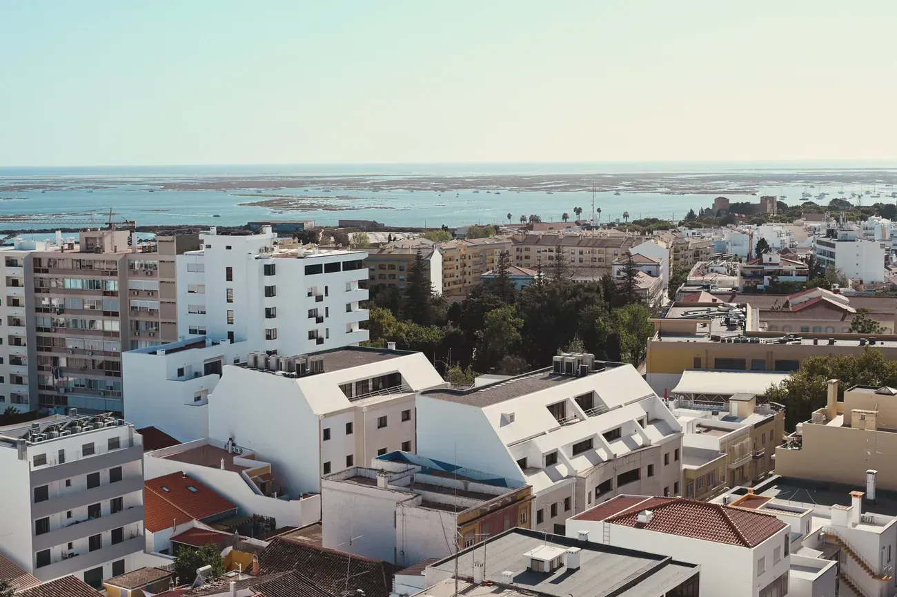 Rooftops of Faro, Portugal, overlooking the Ria Formosa lagoon with moored sailboats and a fort