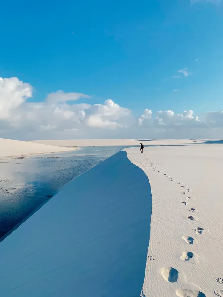 Footprints along a dune ridge above a lagoon in Lencois Maranhenses