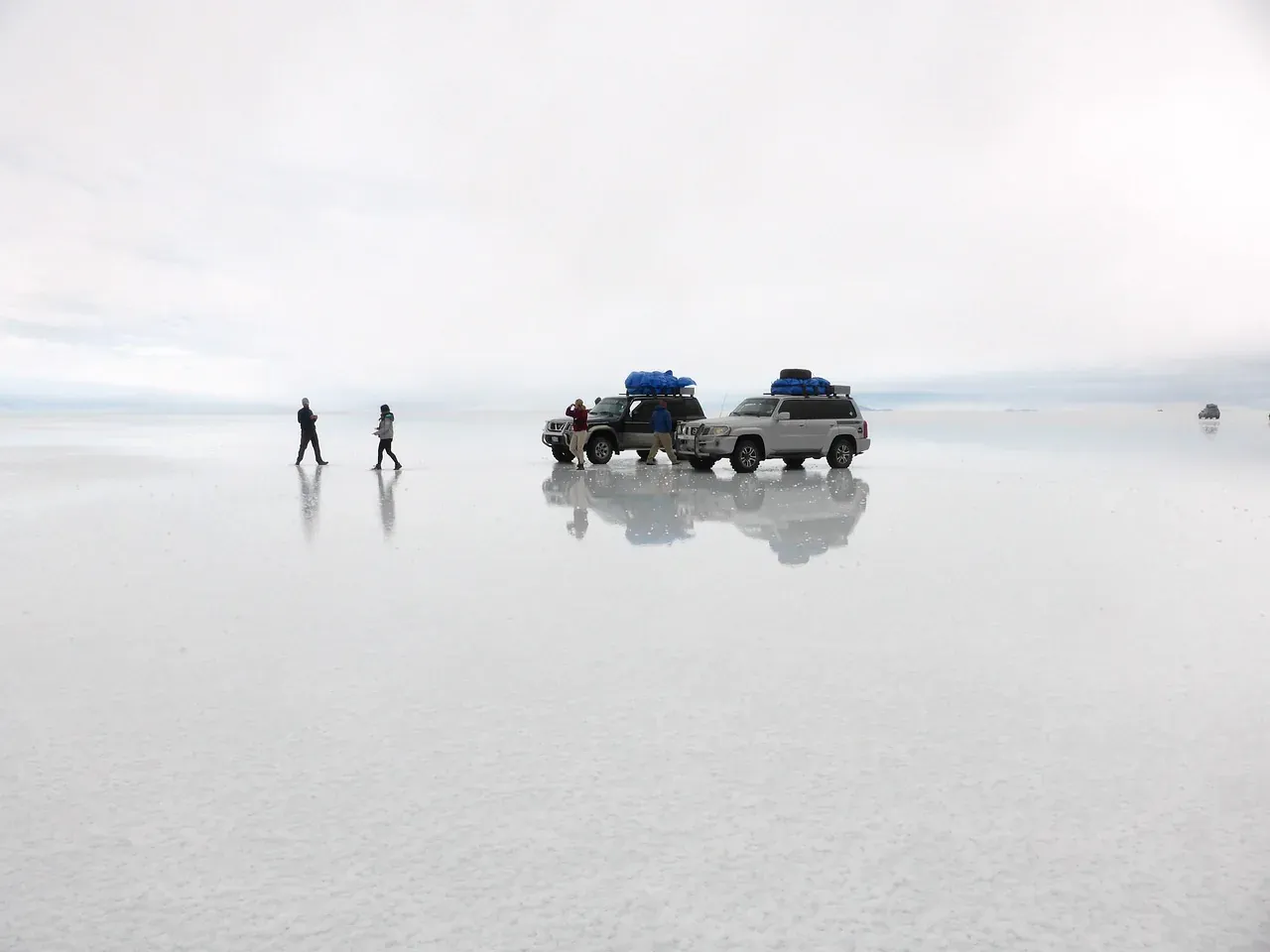 Four-wheel drives and visitors on the mirror-like surface of the Salar de Uyuni