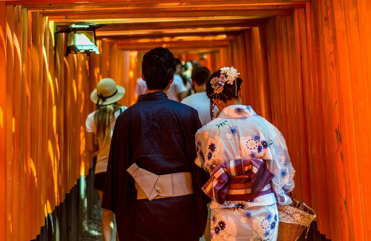 Visitors in kimono walking under the torii gates at Fushimi Inari-taisha in Kyoto