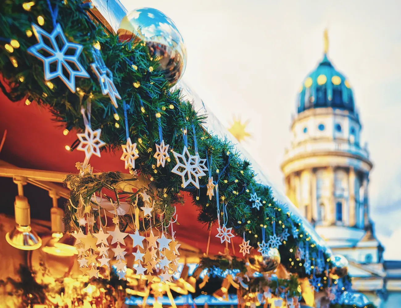 Star decorations on a Christmas market stall with a cathedral dome behind on Gendarmenmarkt in Berlin