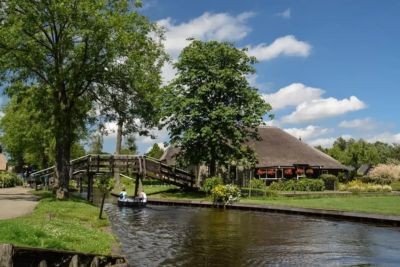 An arched wooden bridge and waterside terrace on the canal at Giethoorn