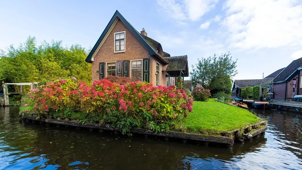 A flowering garden island in front of a brick house on the canal at Giethoorn