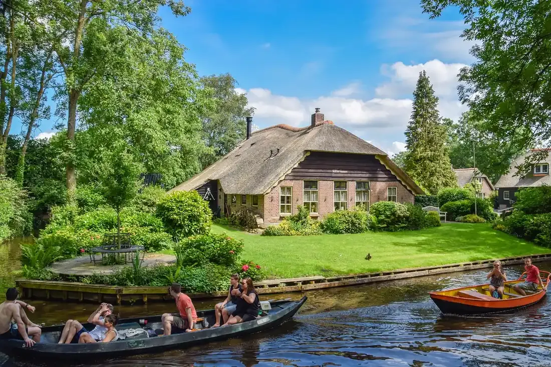 Small electric boats passing thatched houses on the canal at Giethoorn