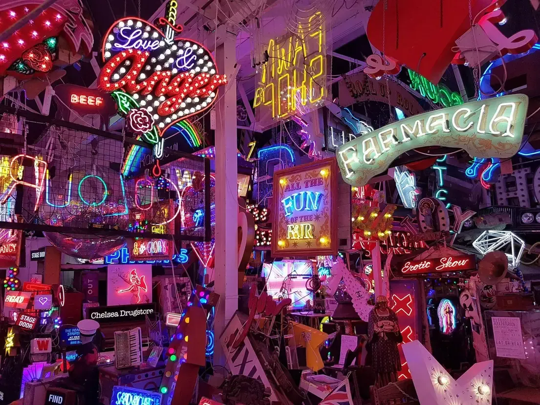 Walls and ceiling packed with salvaged neon signs glowing inside God's Own Junkyard in Walthamstow, London