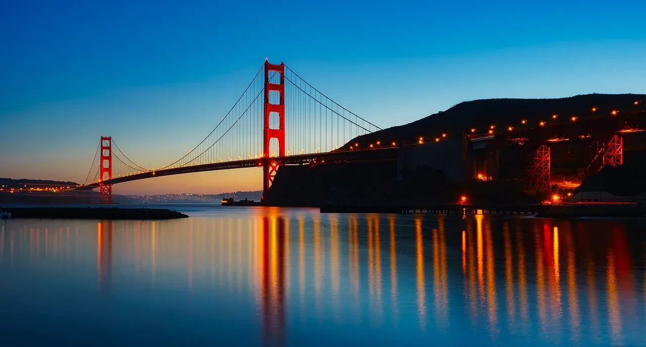 The Golden Gate Bridge lit at dusk across the strait in San Francisco