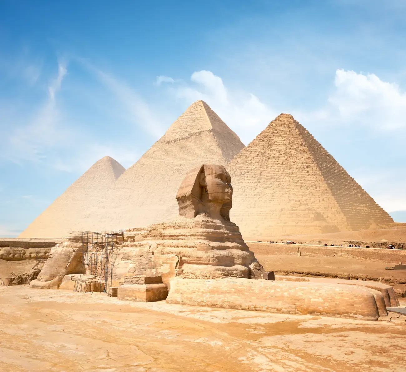 The Great Sphinx of Giza in front of the pyramids of Khafre and Khufu under a blue sky, Giza.