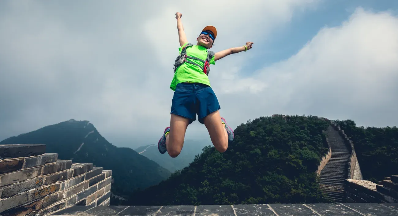A hiker jumping for joy on the Great Wall of China