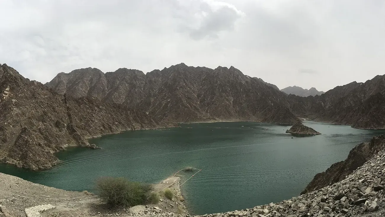 The green reservoir of Hatta Dam between the Hajar mountains