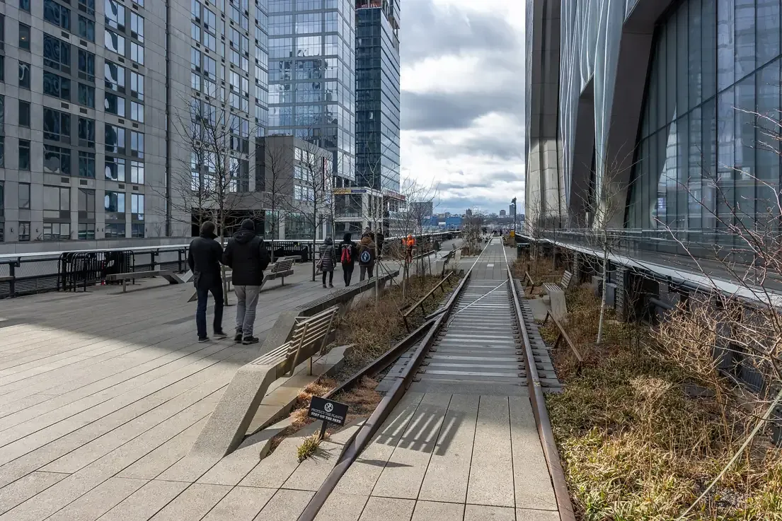 Walkers on the High Line beside the preserved rail tracks, New York City