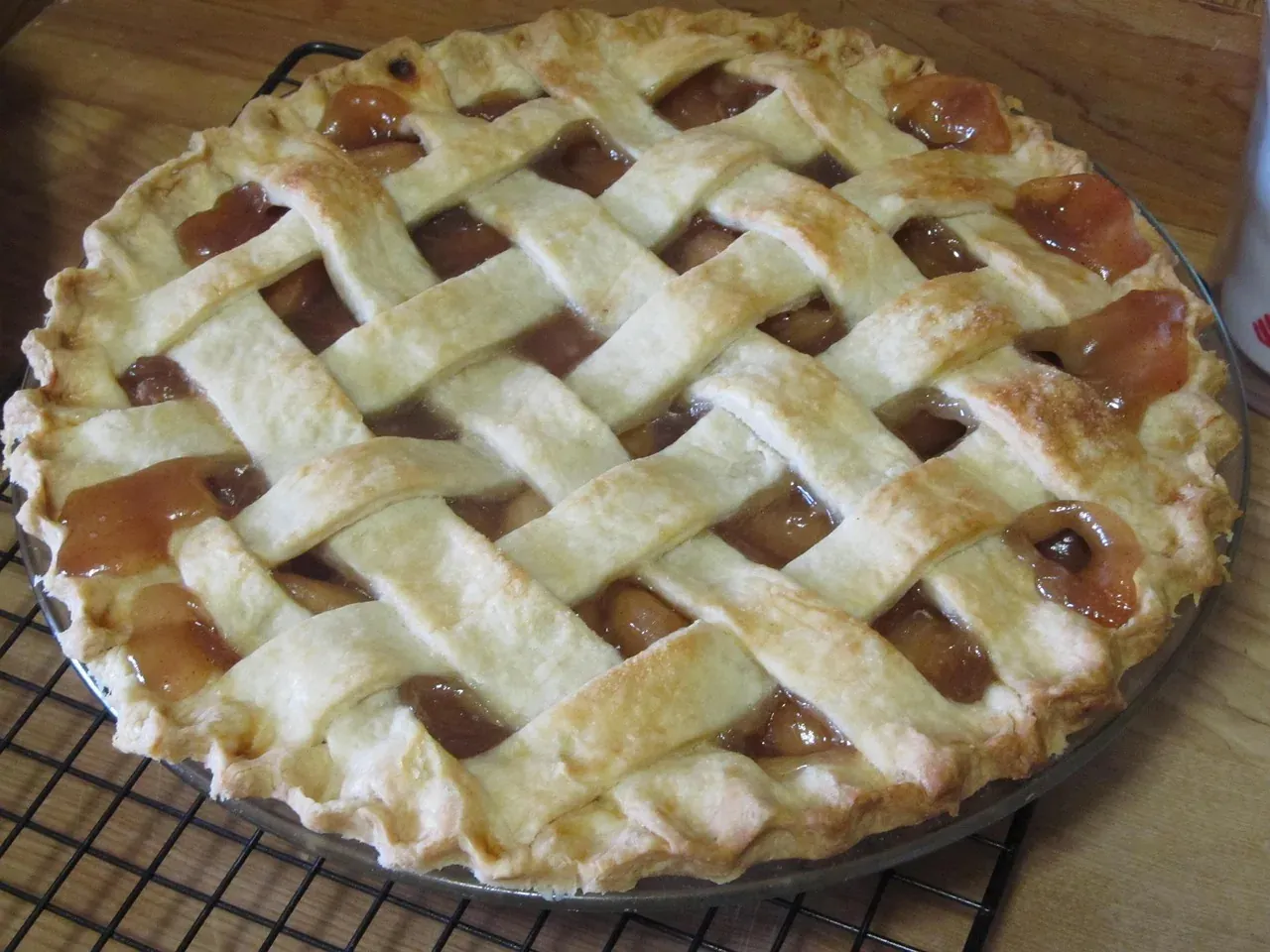 A homemade American apple pie with a golden lattice crust cooling on a wire rack