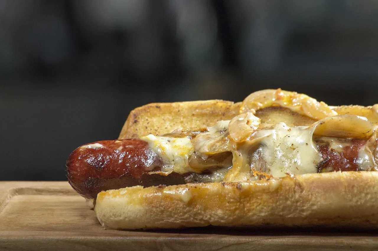 A hot dog in a bun with mustard and toppings