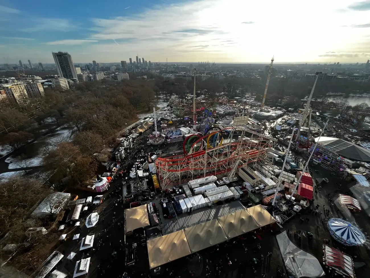Aerial view of Hyde Park Winter Wonderland among the trees of Hyde Park, with the London skyline behind