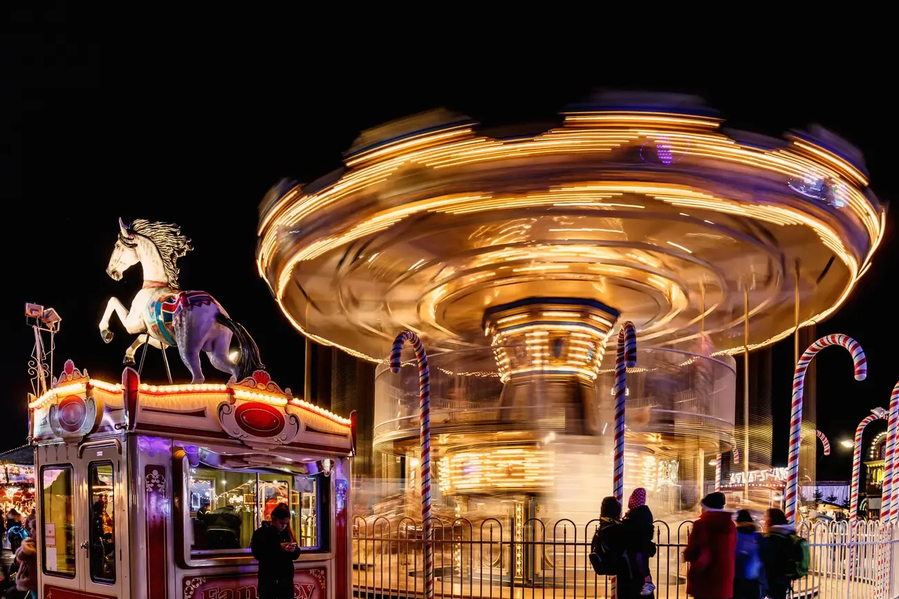 Spinning carousel and a white horse figure at the funfair of Hyde Park Winter Wonderland at night
