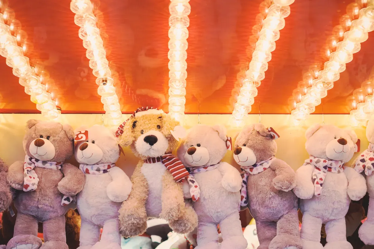 Teddy bear prizes under bright bulbs at a funfair game stall at Hyde Park Winter Wonderland in London