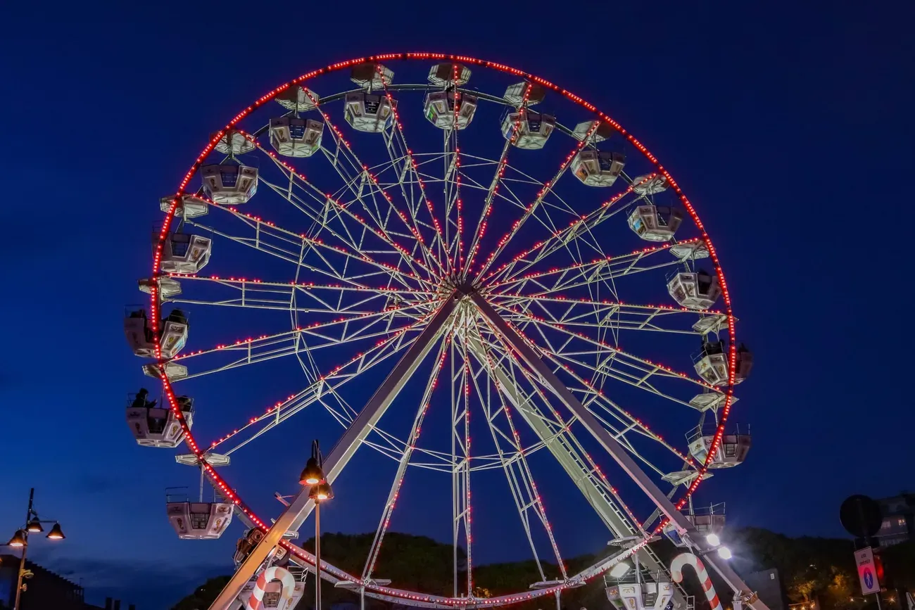 Ferris wheel lit with red lights against a deep blue night sky