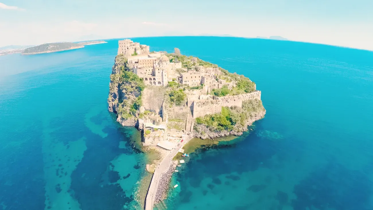 Aerial view of a historic castle on a volcanic islet in Ischia, Italy