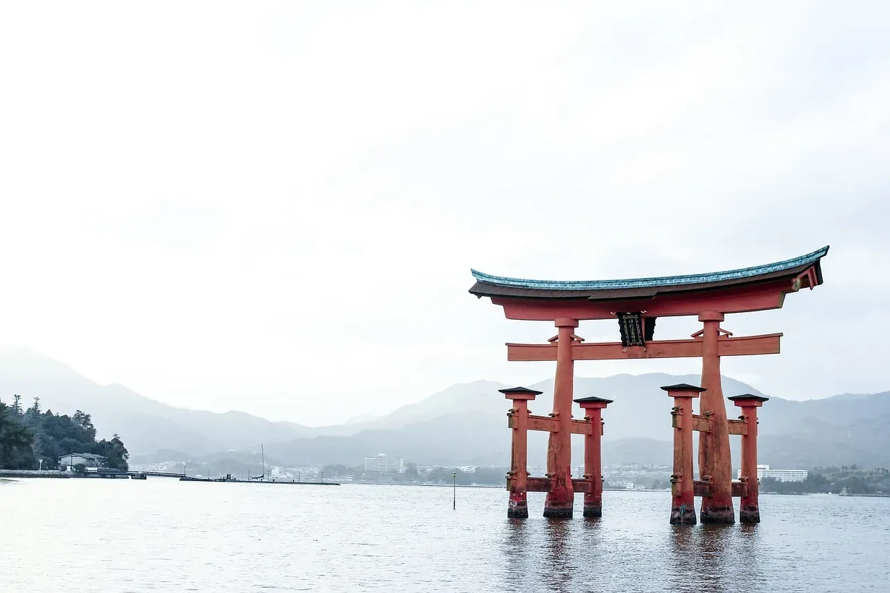 The torii of Itsukushima Shrine in morning haze over the water at Miyajima