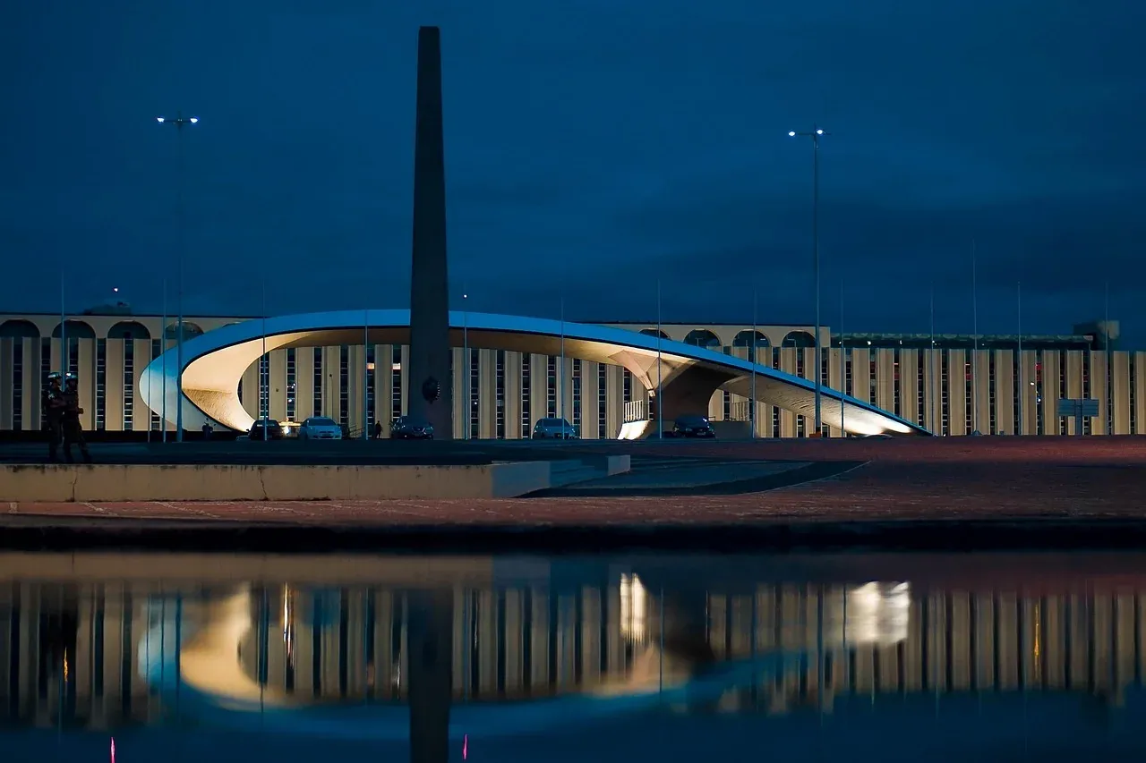 The arches of the Juscelino Kubitschek bridge reflected in Lake Paranoa at dusk