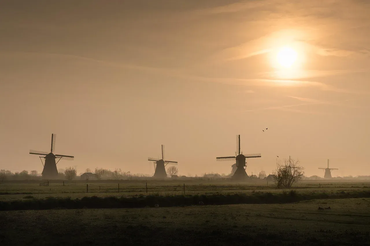 The Kinderdijk windmills silhouetted in morning mist over the polder