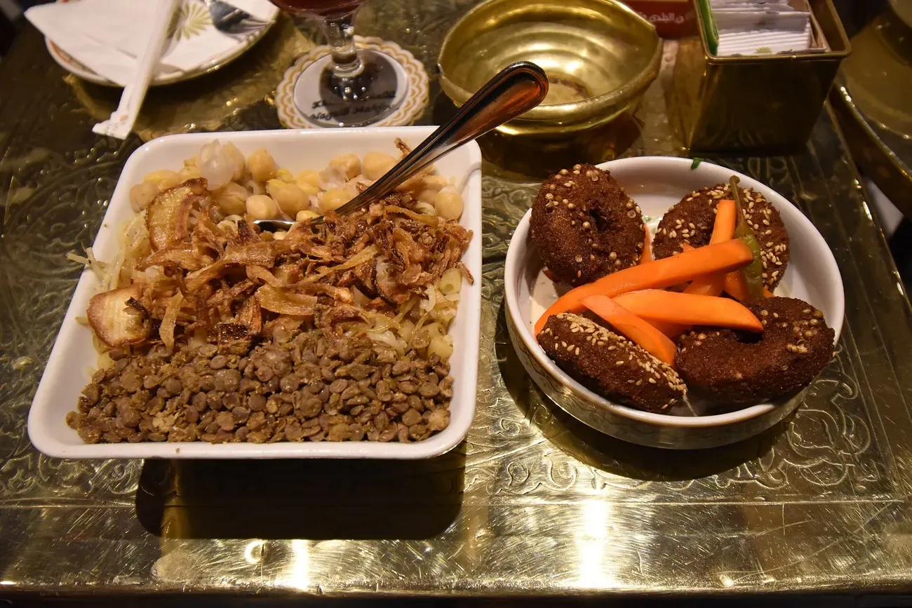 A bowl of koshari with its tomato sauce and fried onions, served in Cairo