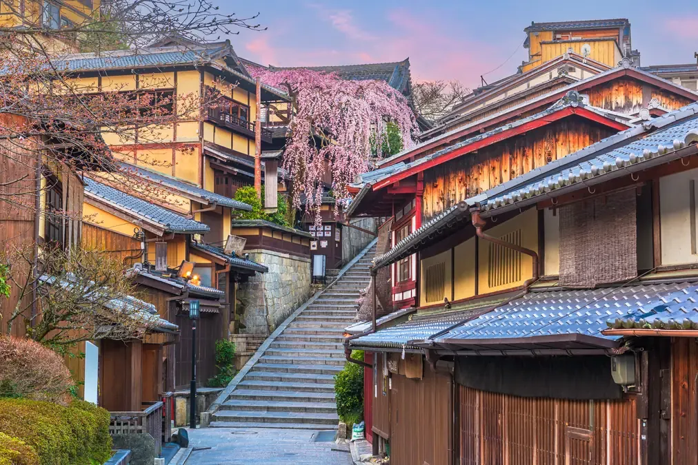 Wooden houses and a weeping cherry tree beside the stone steps of the historic Higashiyama district in Kyoto at dawn