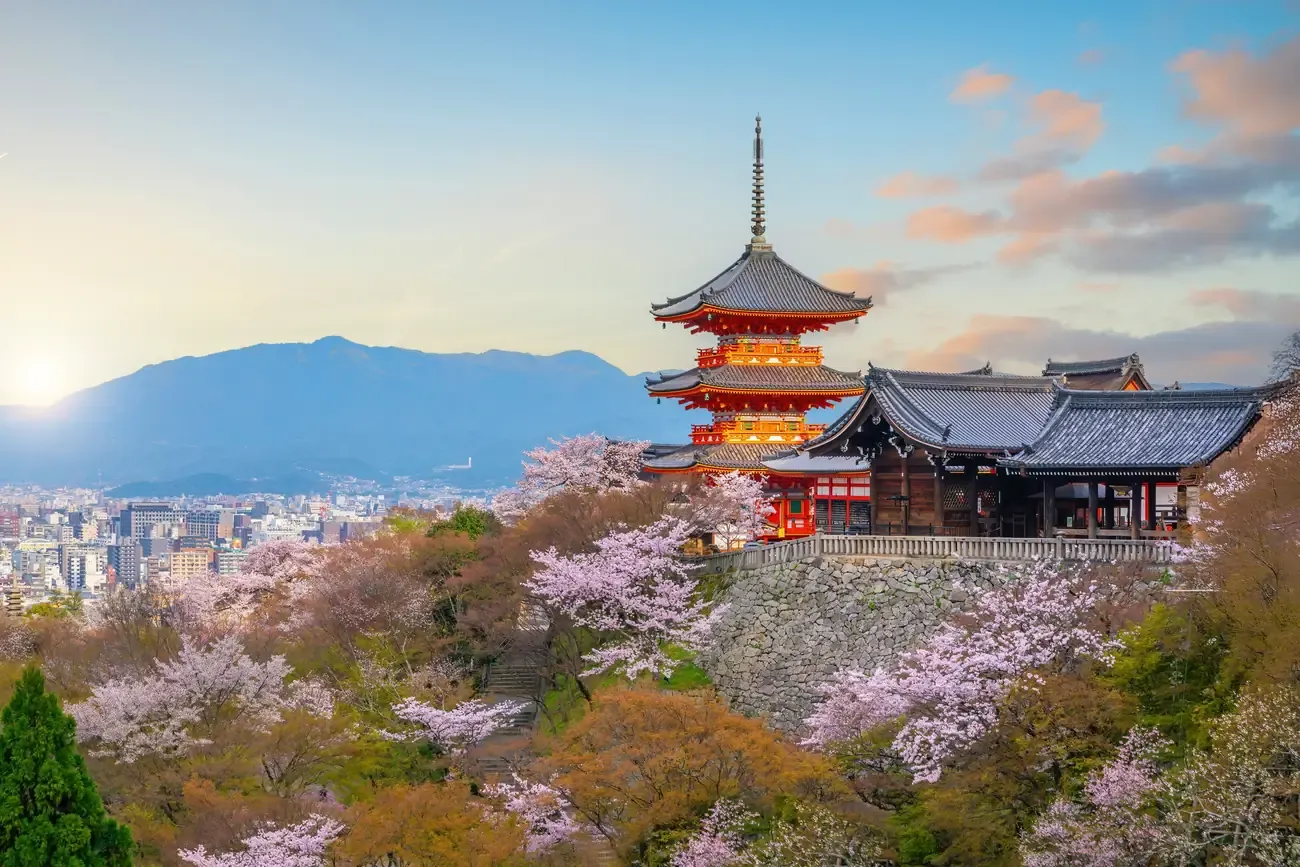The pagoda of Kiyomizu-dera framed by cherry blossoms at sunset in Kyoto