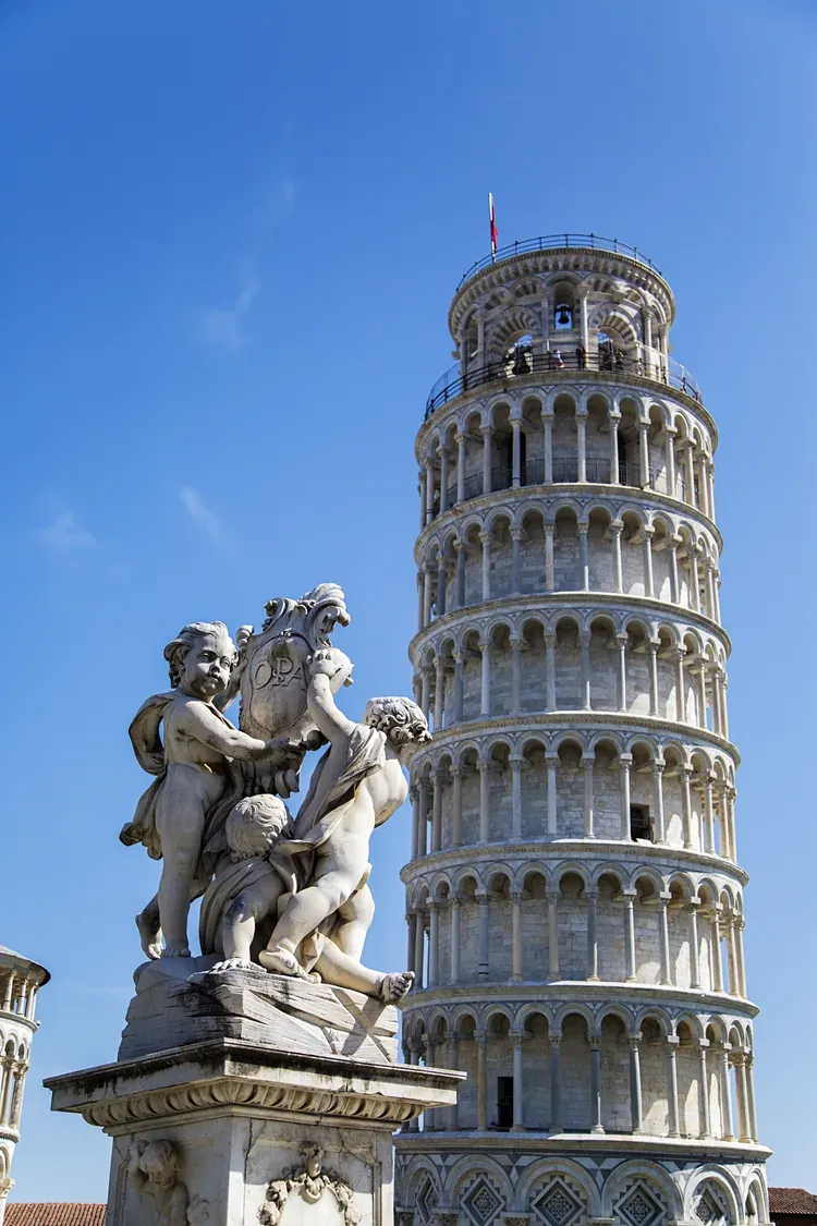 A cherub statue in the foreground of the Leaning Tower of Pisa