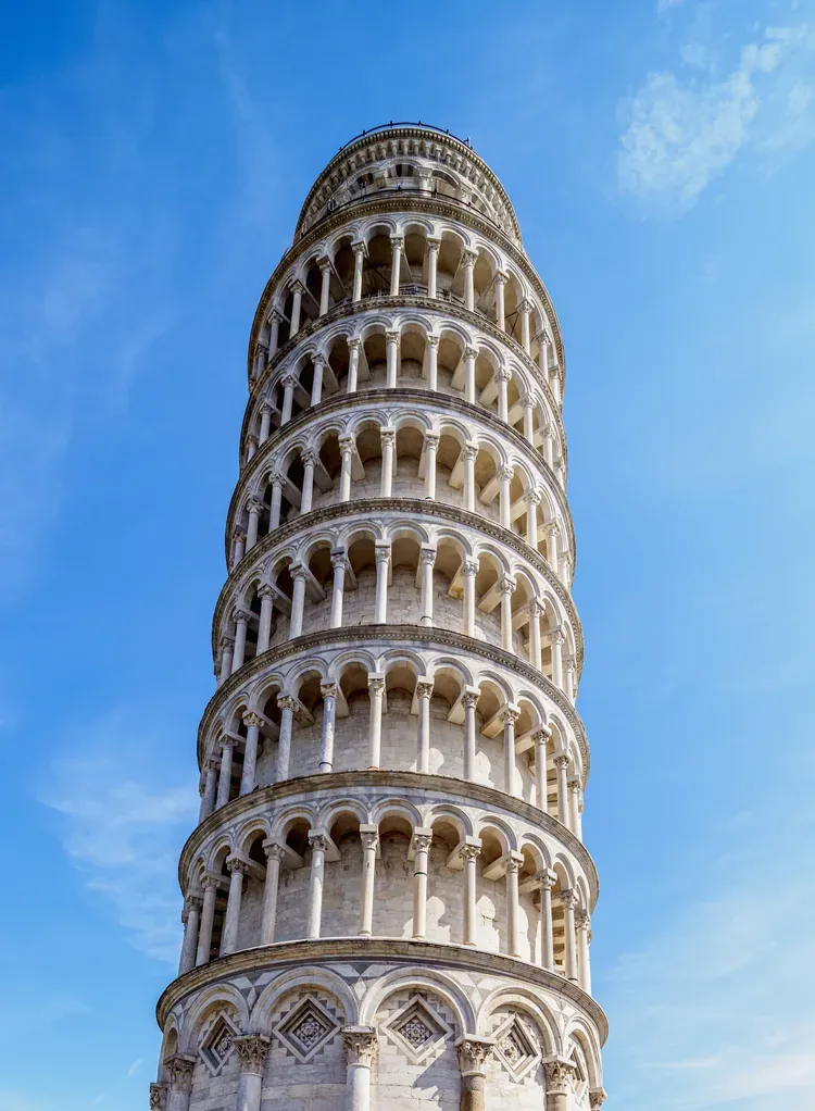 Close-up view of the Leaning Tower of Pisa's arched marble tiers against a blue sky