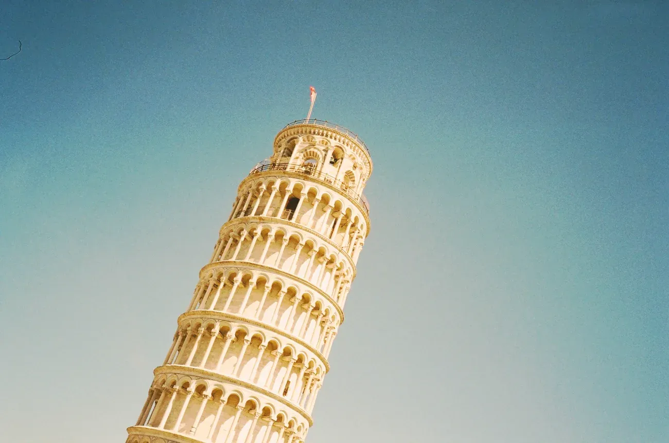 The Leaning Tower of Pisa in warm golden light against a blue sky