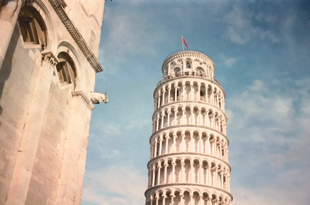 Low-angle view of the Leaning Tower of Pisa beside the corner of the cathedral
