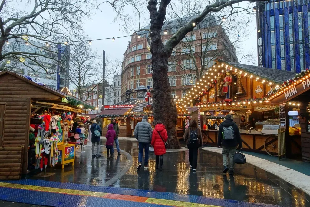 Christmas market chalets and shoppers in Leicester Square, London, in winter