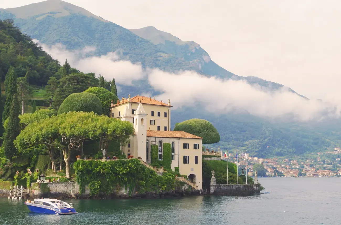 Villa del Balbianello on its wooded promontory above Lake Como with low cloud on the mountains