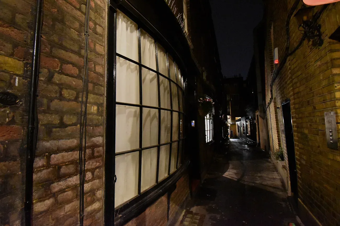 The bow fronted Georgian shopfront and narrow lamplit alley of Goodwin's Court in London